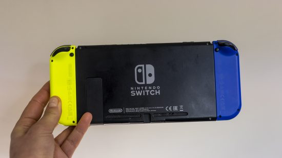 The original Nintendo Switch being held in hand to show the back